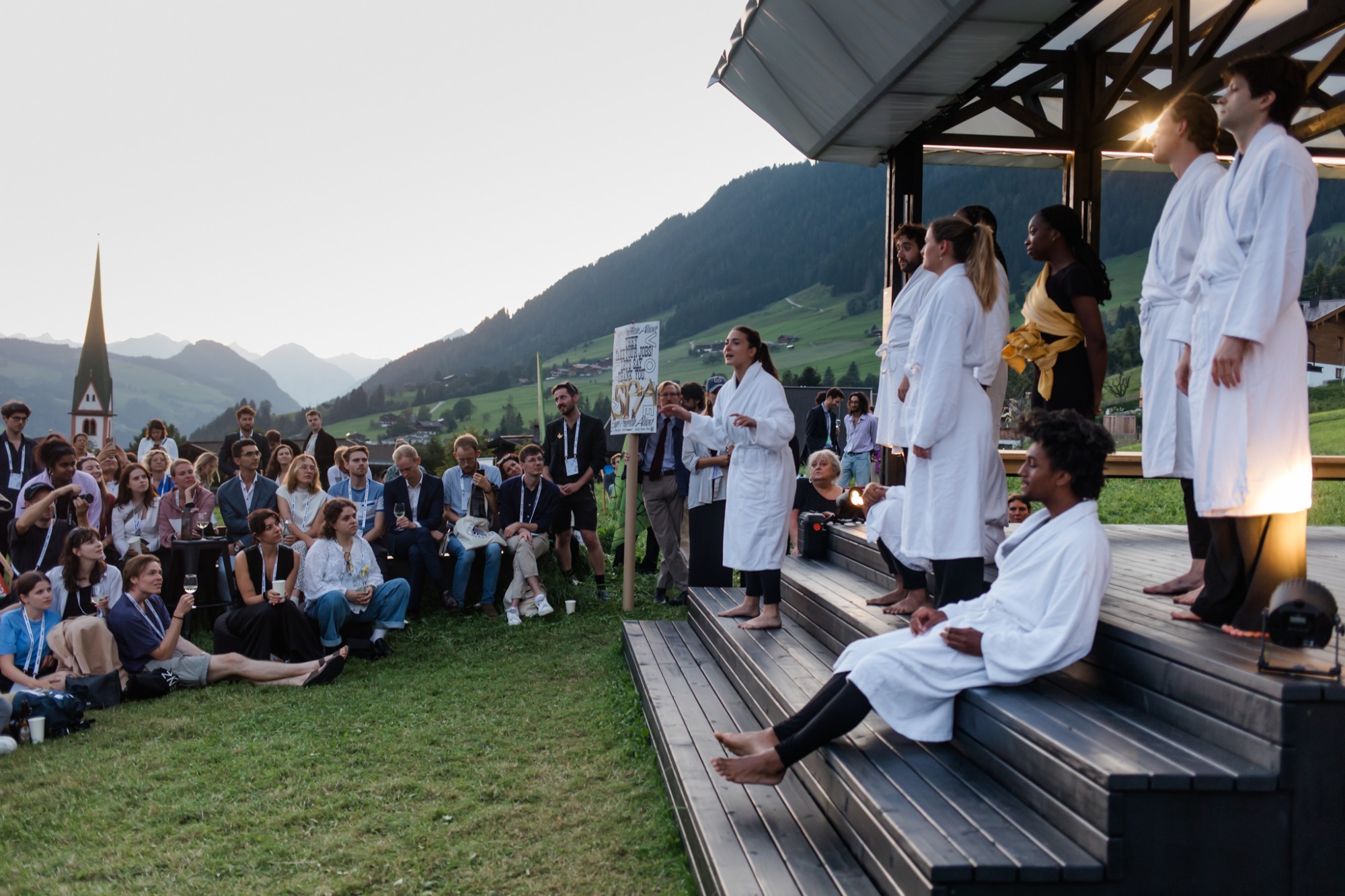 VIENNA DESIGN WEEK x EUROPEAN FORUM ALPBACH, election night: the performance in white bathrobes on the stage steps, the audience on the lawn